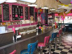 the interior of a diner with pink and blue chairs