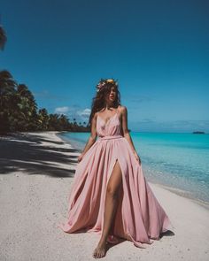 a woman in a pink dress sitting on the beach