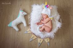 a baby is laying on a white blanket next to a toy unicorn and a wooden horse