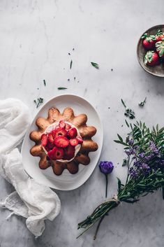 a cake with strawberries is on a plate next to some flowers and lavenders