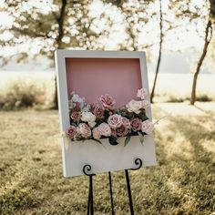 an easel with flowers on it in the grass