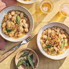 three bowls filled with food on top of a table next to beer glasses and utensils