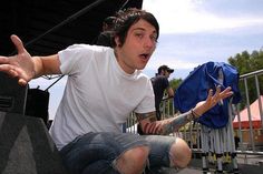 a young man sitting on the ground with his hands in the air and one hand out