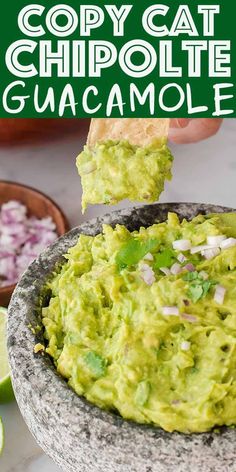 a person dipping guacamole into a bowl with tortilla chips on the side