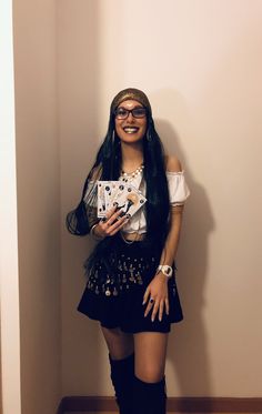 a woman with long black hair and glasses standing in front of a wall