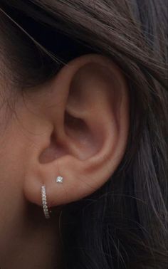 a woman's ear is shown with two small diamond hoops on the side