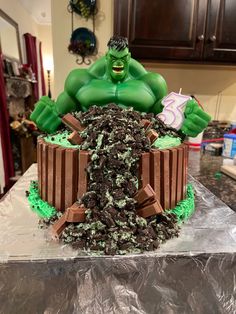 I made this Hulk Smash Birthday cake using the Hulk bank character from Amazon,  chocolate cake mix, vanilla Marshmallow icing with greens food colors, crushed mint Oreos and Kit Kat’s. Birthday Cake For My Son, The Hulk Party Ideas, Hulk 2nd Birthday Party, Incredible Hulk Birthday Cake, Easy Hulk Cake, Simple Hulk Cake