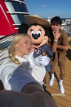 two people pose with mickey mouse on a cruise ship