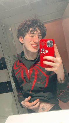 a man taking a selfie in the mirror with his cell phone and spiderman shirt on