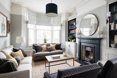 a living room filled with furniture and a fire place in front of a mirror on the wall