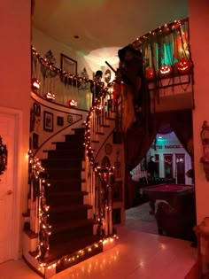 a staircase decorated with lights and decorations for halloween time in a house that is lit up at night