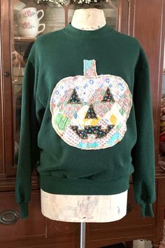 Easing into Fall & Halloween With Our Vintage Quilt Pumpkin Appliqué Sweatshirts  Jack 'O Lantern  Tag Size:  Jerzees                  MEDIUM                   (Dark Green) Our Vintage Quilt Pumpkin Sweatshirts are a Great Staple Piece for Your Closet this Fall. Whether You're Going to the Pumpkin Patch on Brisk Day or Sitting Around A Bonfire in the Evening, They Are Great For Layering. Measurements are Taken Lying Flat: Shoulder to Shoulder: 19 1/2" Underarm to Underarm: 20" Length Shoulder Se Jack O Lantern Sweatshirt, Vintage Quilt Clothing, Quilted Pumpkin Sweatshirt, Winter Costume Long Sleeve Tops, Costume Long Sleeve Winter Tops, Fall Costume Party Long Sleeve Tops, Long Sleeve Tops For Costume Party, Fall, Long Sleeve Tops For Costume Party In Fall, Cotton Long Sleeve Costume Top