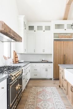 a kitchen with white cabinets and an area rug in front of the stove top oven