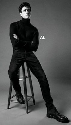 a man sitting on top of a stool in front of a black and white photo