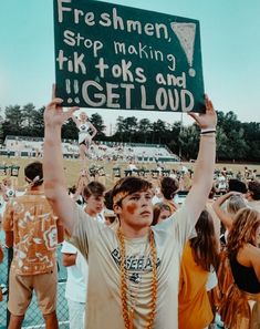 a young man holding up a sign in front of a crowd at a football game