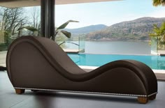 a modern chaise lounge chair in front of a large window overlooking a swimming pool