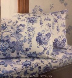 two blue and white pillows sitting on top of a couch next to a framed photo