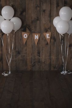 some white balloons are in front of a wooden wall