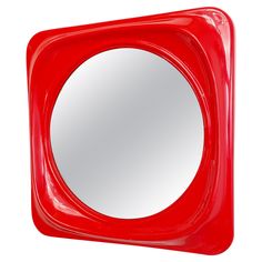 a red square shaped mirror sitting on top of a white wall