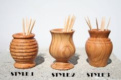 three wooden vases with sticks sticking out of them on top of a stone slab