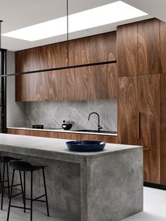 a modern kitchen with an island countertop and bar stools in front of it