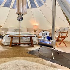 a bed sitting inside of a white tent next to a table and two chairs on top of a rug