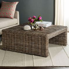 a wicker coffee table with pink flowers on it in a living room next to a couch