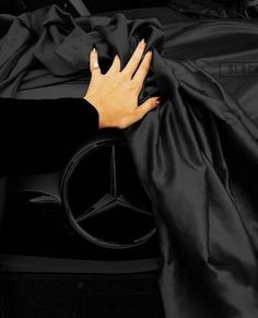 a woman's hand on the hood of a black mercedes benz car covered by a black cloth