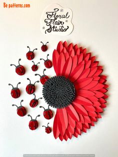 a red paper flower surrounded by ladybugs on a white background with the words floral flam studio above it