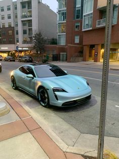 a blue sports car is parked on the side of the road in front of some buildings