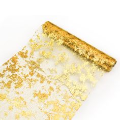 a piece of gold and white glitter paper on a white surface with the edge partially cut off