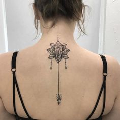 the back of a woman's neck with a flower and arrow tattoo on it