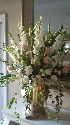 a vase filled with white and pink flowers sitting on top of a table next to a mirror