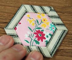 a hand is holding a piece of fabric with flowers on it