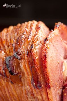 sliced ham sitting on top of a cutting board next to another piece of meat in the background