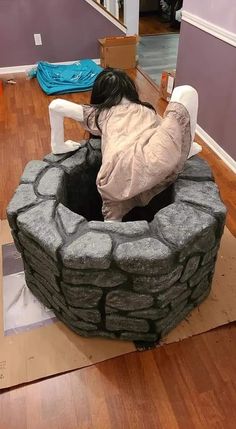 a woman laying on the floor in front of a fire pit made out of rocks