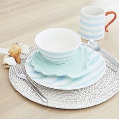 a place setting with plates, cups and utensils on a wooden table top