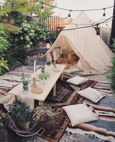 a tent is set up in the middle of a garden with lots of pillows and blankets