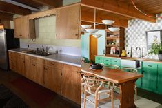 a kitchen with green cabinets and wooden floors, an island table in front of the sink