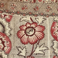 a red and white floral design on a piece of cloth with flowers in the center