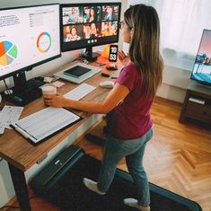 a woman standing in front of two computer monitors