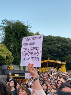 a person holding up a sign in front of a crowd