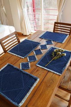 a wooden table topped with blue placemats and napkins on top of it