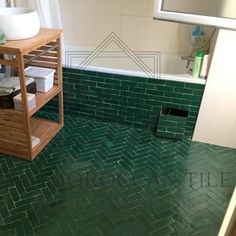 a bathroom with green tiles and a wooden shelf in the corner next to the bathtub