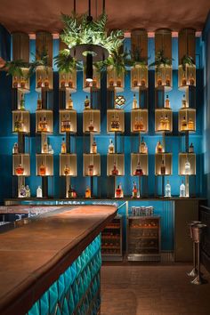 a blue bar with lots of bottles on the shelves and lights hanging from the ceiling