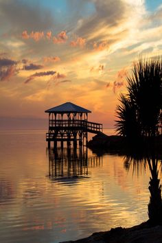 a pier sits on the water as the sun sets