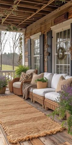 a porch covered in wicker furniture and potted plants on top of the wooden floor