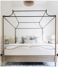 a bedroom with a canopy bed and blue pillows on the pillowed bedspread