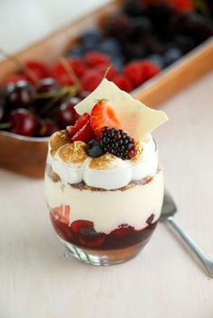 a dessert in a glass with berries and whipped cream on top