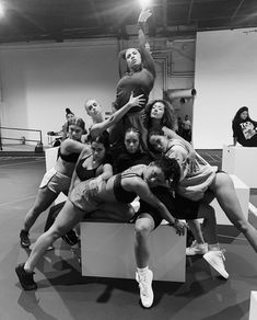 a group of young women sitting on top of each other in front of a mirror